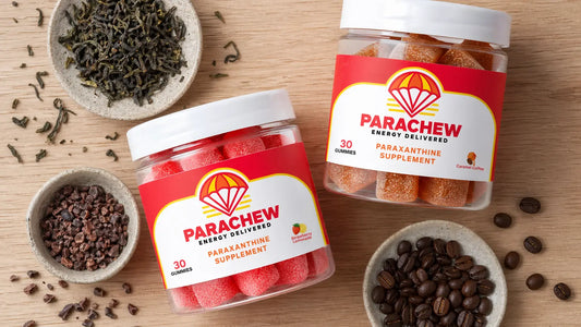 Parachew Energy Gummies bottle arranged on a lab bench alongside tea leaves, coffee beans, and cacao nibs representing natural paraxanthine sources